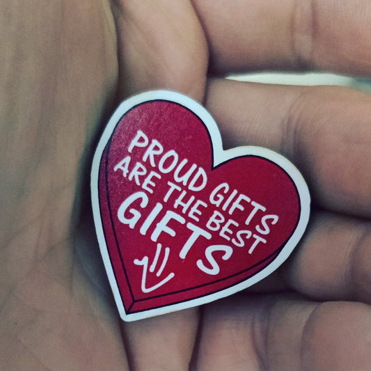 A hand holding a red heart-shaped magnet with white text that reads 'PROUD GIFTS ARE THE BEST GIFTS' and a small Proud Smiley face